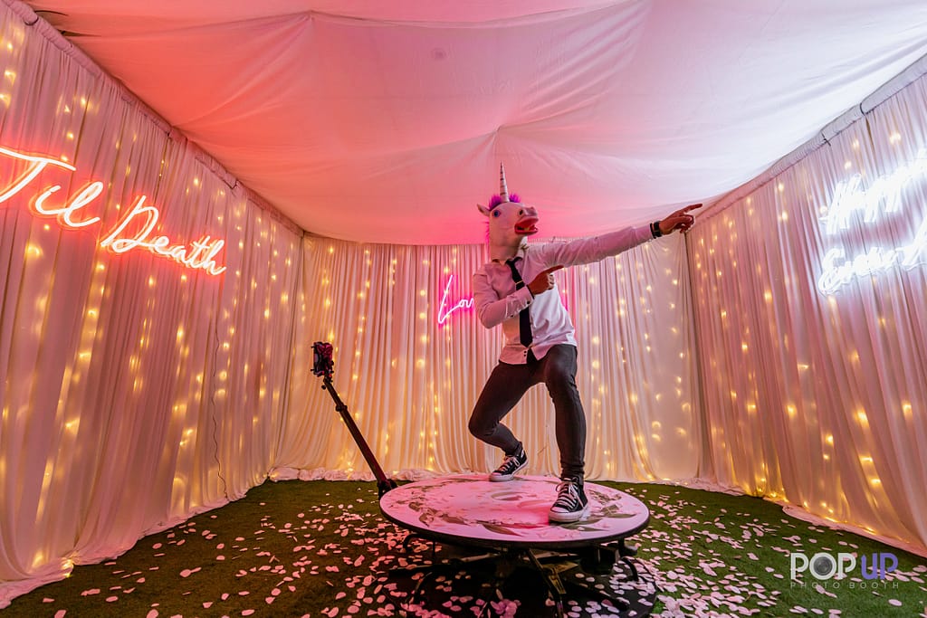 Man wearing unicorn mask posing on 360 photo booth
